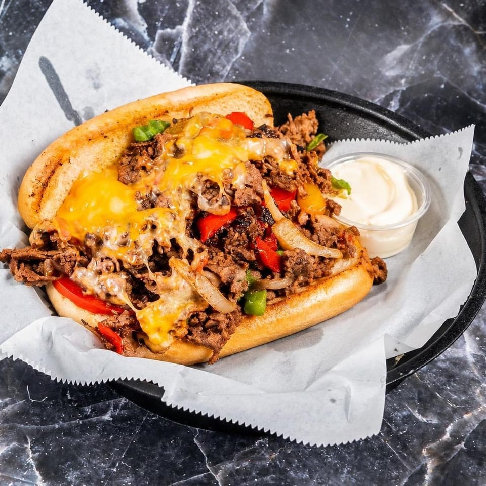 Loaded cheesesteak sandwich with shaved beef, melted cheese, peppers, and onions served with creamy dipping sauce.